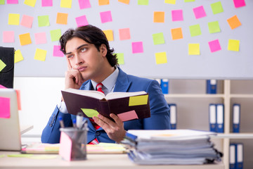 Young male handsome employee in conflicting priorities concept 