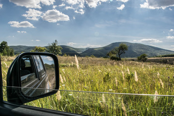 Suv rear view mirror shot while off roading on a beautiful field.