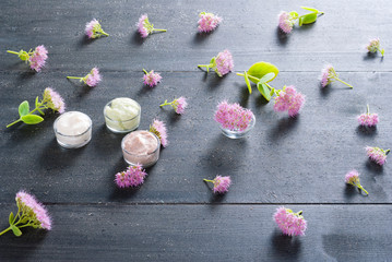 moisturizer with pink flowers on old black wood table