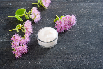 moisturizer with pink flowers on old black wood table