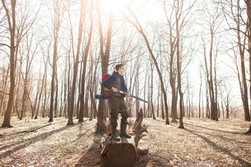 Portrait of yang hunter with a backpack and a gun on the forest