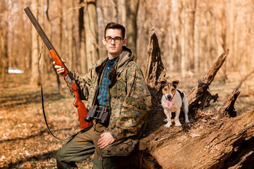 Portrait of a yang hunter with a dog on the forest