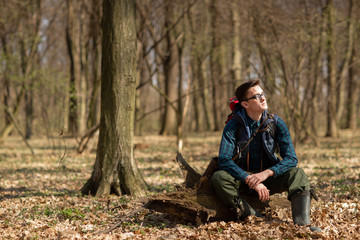 Naklejka na ściany i meble Young man with backpack hiking in the forest. Nature and physical exercise concept