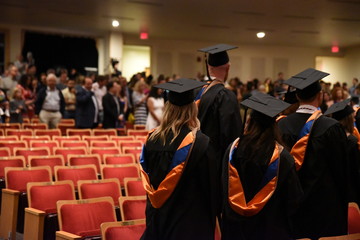 College graduates file out of an auditorium after the commencement ceremony.