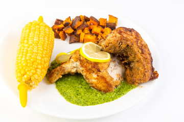 Overhead View of Deep Fried Chicken on Bed of Pesto with Corn on Cob and Sweet Potatoes