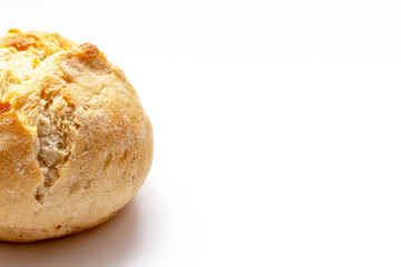 Cropped baked wheat bun with golden crust on white background with copy space, bakery and grocery concept