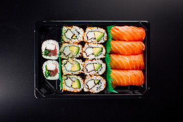 Sushi Set sashimi and sushi rolls served on plastic plate and dark background