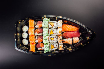 Japanese cuisine. Sushi set on a plastic ship over dark background.
