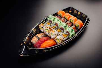 Japanese cuisine. Sushi set on a plastic ship over dark background.