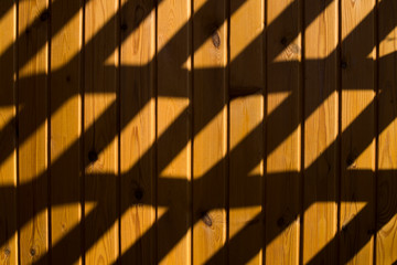 Shadow and light. Sunlight on a wooden wall through decorative grille