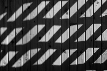 Shadow and light. Sunlight on a wooden wall, passing through a decorative lattice. Black and white