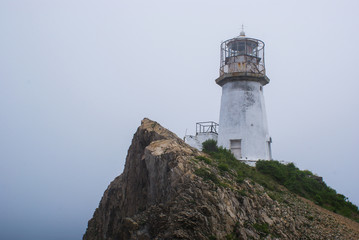 Cape Briner. Primorsky Krai. At the top of the cliff, there is an old lighthouse hidden in the fog