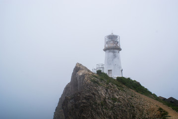 Cape Briner. Primorsky Krai. At the top of the cliff, there is an old lighthouse hidden in the fog