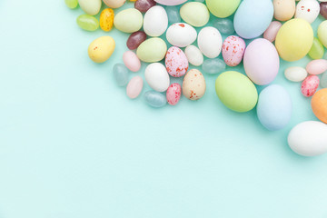 Happy Easter concept. Preparation for holiday. Easter candy chocolate eggs and jellybean sweets isolated on trendy pastel blue background. Simple minimalism flat lay top view copy space