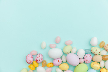 Happy Easter concept. Preparation for holiday. Easter candy chocolate eggs and jellybean sweets isolated on trendy pastel blue background. Simple minimalism flat lay top view copy space