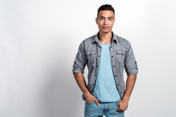 Fototapeta premium Studio shoot of a handsome man against the white wall, holding his hands in pockets
