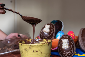 chocolate derretido cayendo desde una cuchara a una taza, huevos de pascua de fondo
