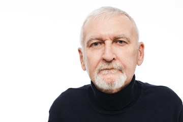 Portrait of old attractive man with gray hair and beard in black sweater dreamily looking in camera over white background isolated