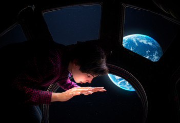 young space tourist in front of the space shuttles windows. elements of this image furnished by nasa