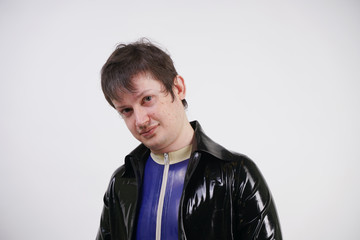 Caucasian nerd chubby man dressed in fashionable latex rubber fetish clothes on white background in Studio