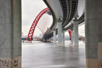 bottom view between concrete pillars on the road bridge with a red arch