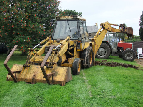 Yellow Digger Digging Out Foundations For An Extinction To A Bungalow With Tractor And Trailer