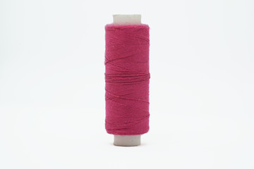 Long plastic skein of pink thread for a sewing machine close-up isolated on a white background.
