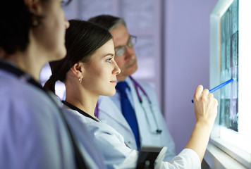 Obraz premium Group of doctors examining x-rays in a clinic, thinking of a diagnosis