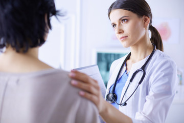 Medical consultation. Female doctor holding a patient by her shoulder, soothing her fear