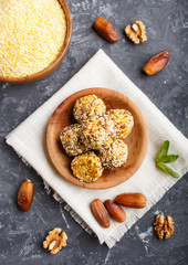 Energy ball cakes with dried apricots, cornflakes, sesame, linen, walnuts and dates on a black concrete  background, top view, close up.
