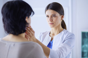 A serious female doctor examining a patient's lymph nodes
