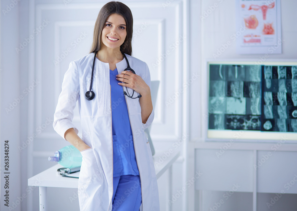 Wall mural portrait of a beautiful doctor standing at hospital and holding her stethoscope