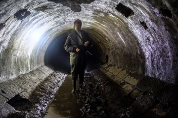 Sewer worker in underground sewer tunnel - obrazy, fototapety, plakaty