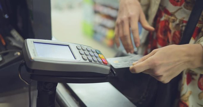 Girl inserts a bank card into the terminal and pays for purchases. Close-up.