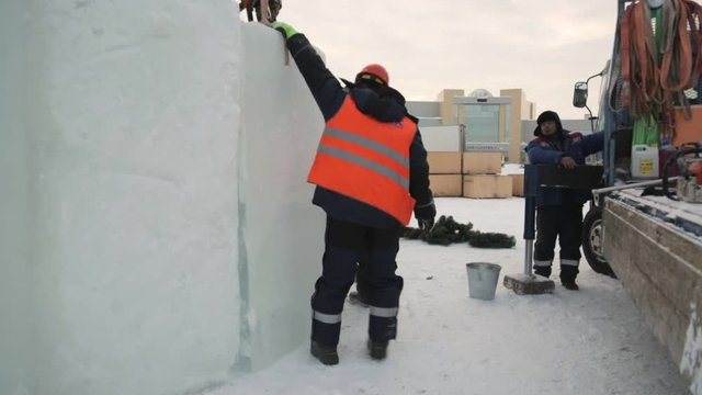 Slinger in a vest and orange helmet joins the ice block