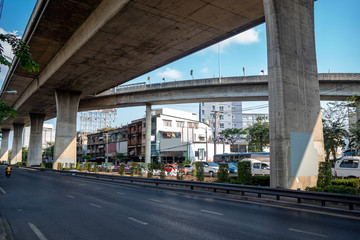 Traffic of the street under the expressway with houses and clear blue sky background