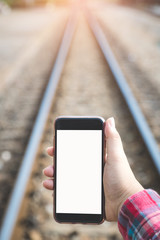 woman's hand holding and using smartphone, black screen with blur railway background. subject is...