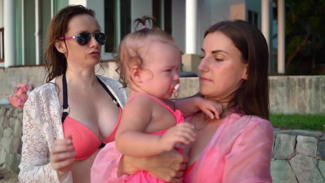 Lesbian Couple With A Child Relaxing On A Beautiful Tropical Beach. Lesbian Couple Calms A Crying Child