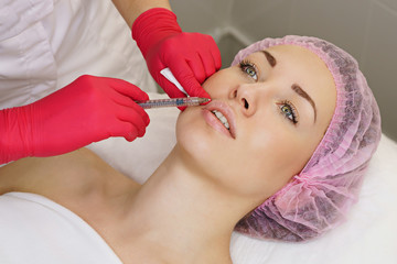 Hands of cosmetologist are close-ups that inject hyaluronic acid into upper lip of a girl. Cosmetic procedure in spa salon. Restorative cosmetology