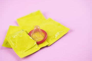 yellow package condom on pink background (World AIDS Day concept), soft focus.