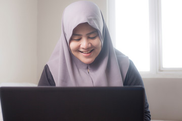 Happy Muslim Woman Working with Laptop in Her Bedroom