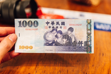 Hand holding a back of NT$1000 (One Thoundsan New Taiwan Dolla) banknote, For tourists and traveler.