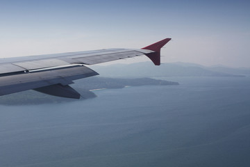 Obraz premium flying and traveling abroad, bird eye view from airplane window on the jet wing on wonderful island beach in vacation summer, journey backgrounds