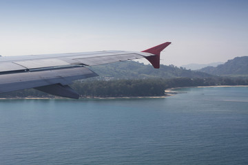 Fototapeta premium flying and traveling abroad, bird eye view from airplane window on the jet wing on wonderful island beach in vacation summer, journey backgrounds