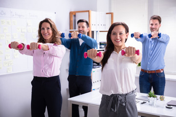 Businesspeople Exercising With Dumbbells