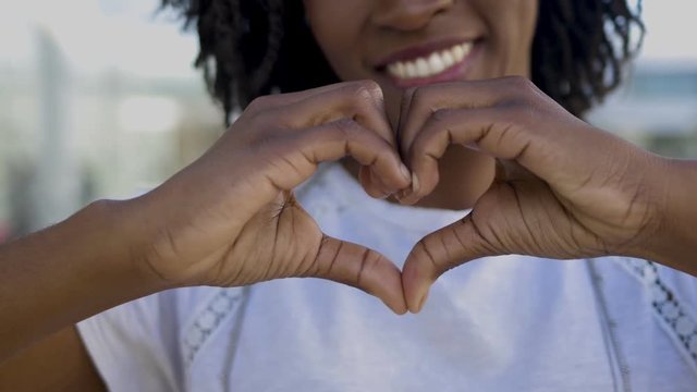 Closeup view of female hands making heart shape. Cropped shot of African American woman holding hands in shape of heart. Gesture concept