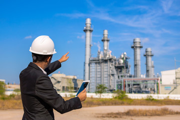 businessman is use smartphone check system at power plant
