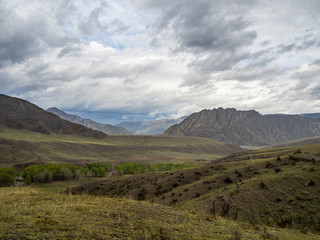 Fototapeta na wymiar Dramatic clouds in the sky over the steppe and mountain peaks in the Altai, Russia