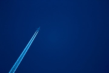  long-haul airplane in the evening sky with contrail