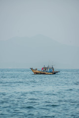 Naklejka premium A beach in Hoi An with tourists, boats and fisherman, Vietnam.